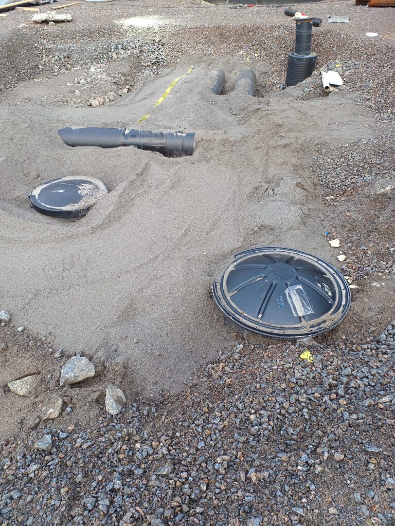 Completed installation of valve wells for underground pipelines in an excavated pit.