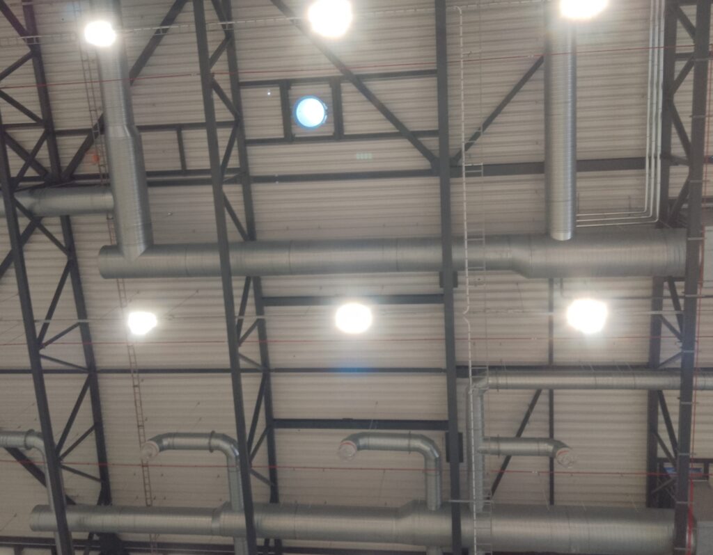 Building services installations mounted on the ceiling of a hall.