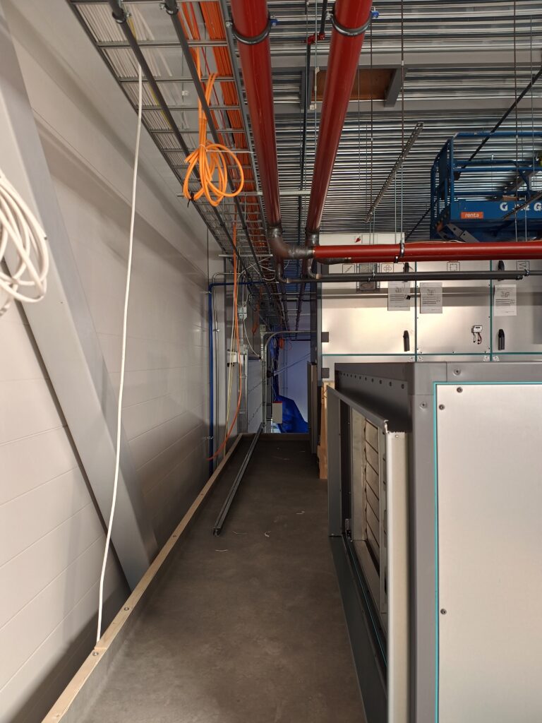 Ventilation unit and heating piping installations in an open space.