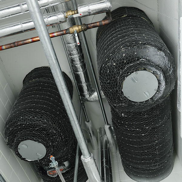 Fire-insulated ventilation ducts and other piping near the ceiling.