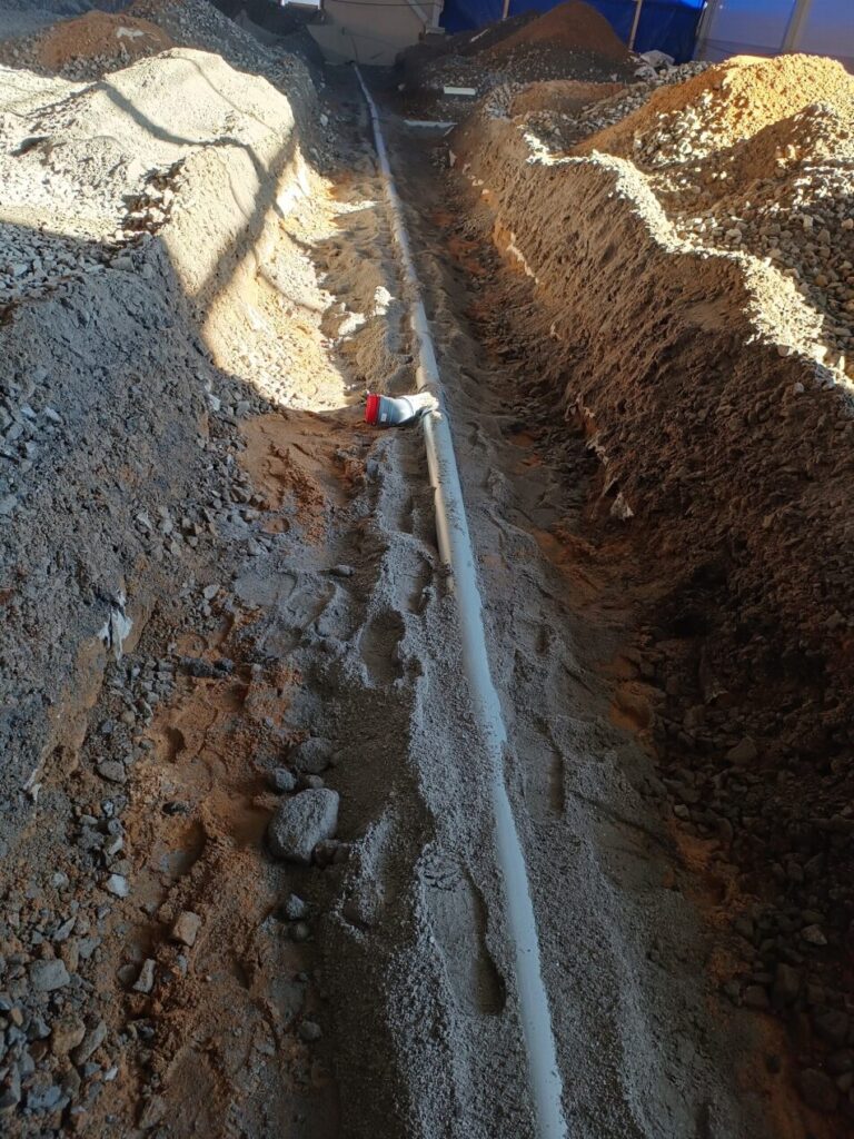 Sewer installation in an excavated sand bed.