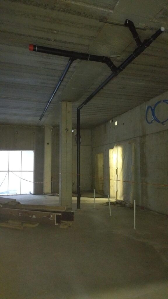 Finished sewer and domestic water pipe installations near the ceiling.