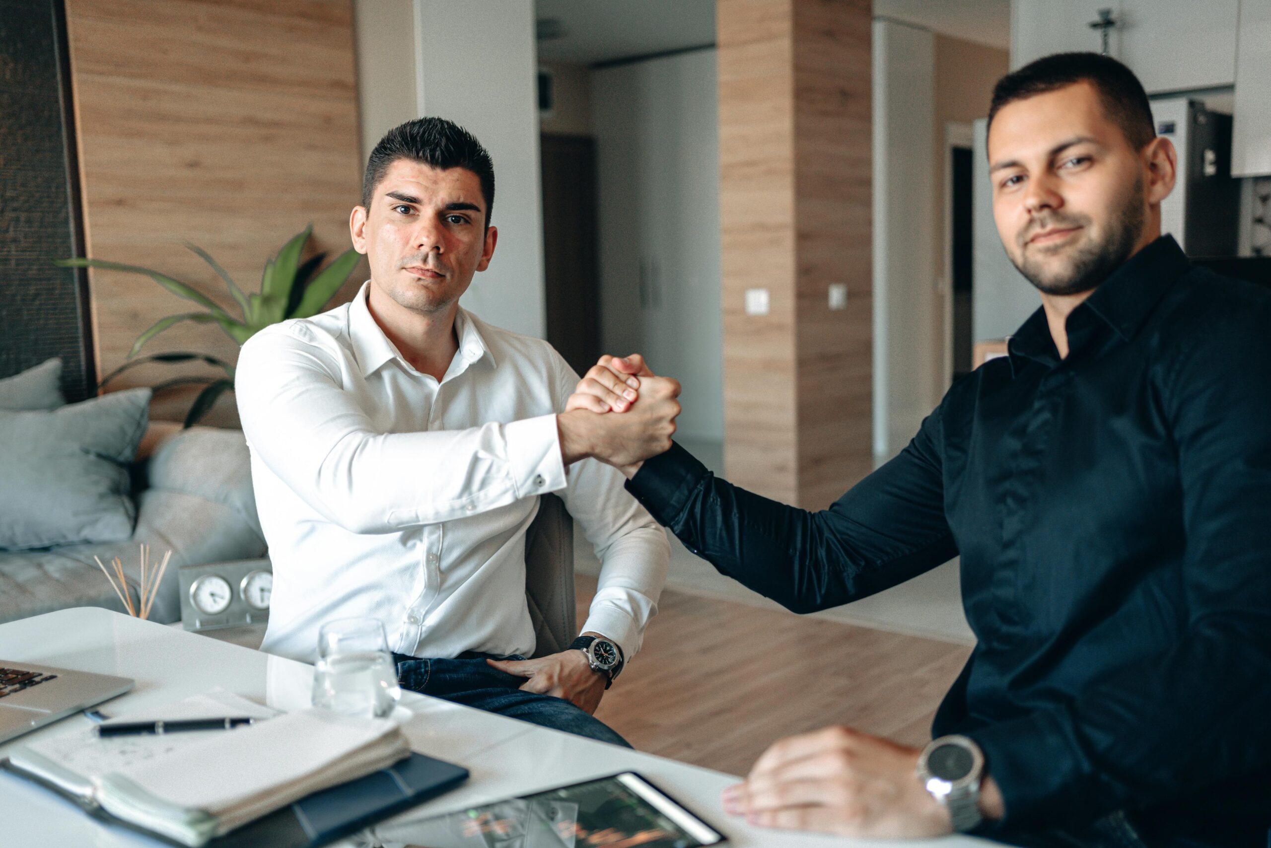 Two businessmen sealing a deal with handshake indoors.